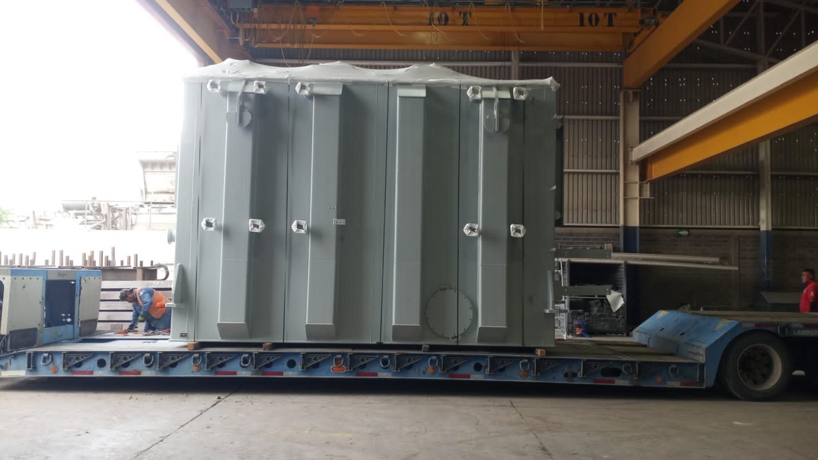 Transformer tank loaded on a lowboy trailer inside the plant